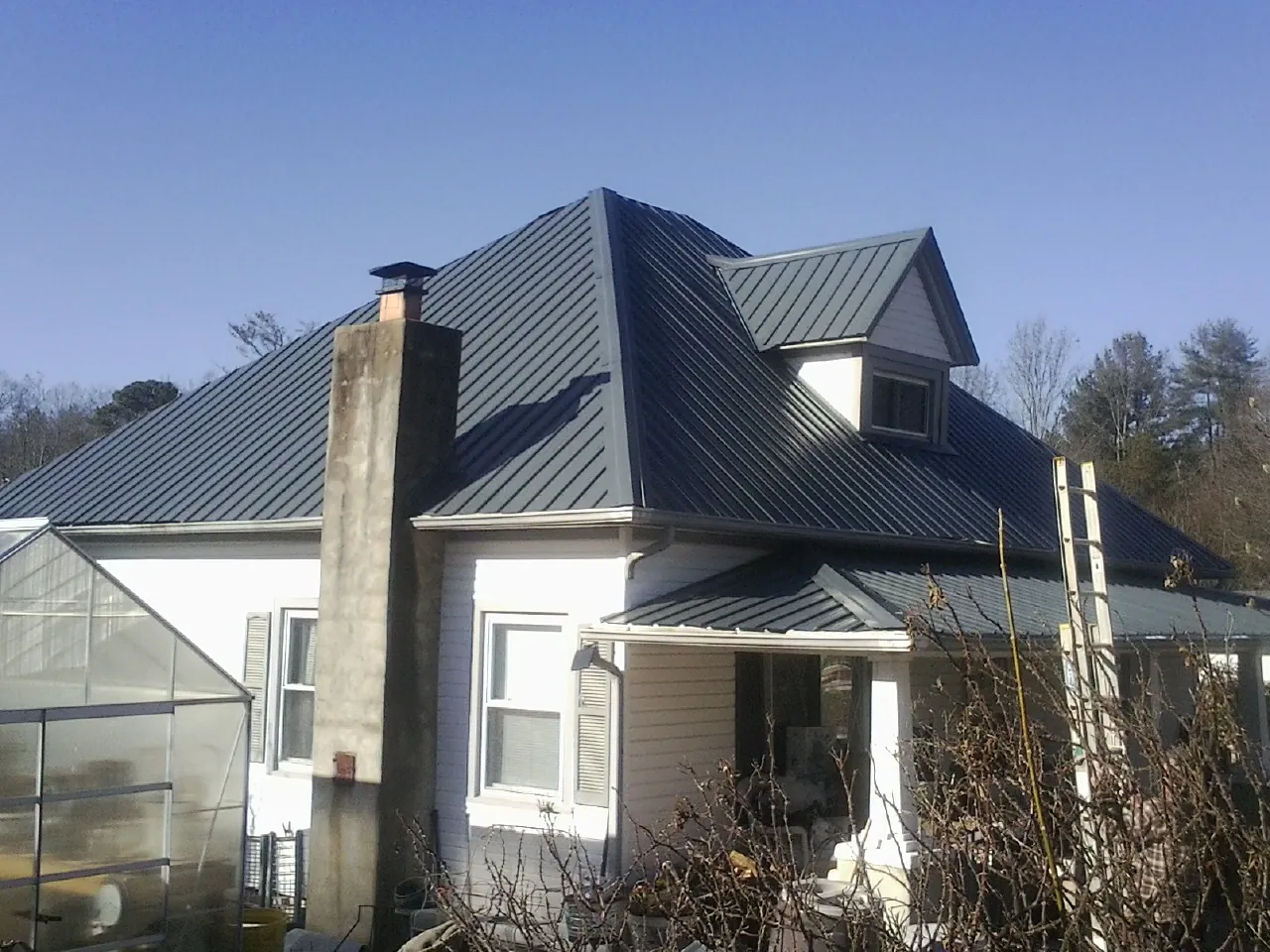 Dark blue standing seam metal roof on a white farmhouse with dormer — Slate & Tile Roof Repair by Roofing Brothers in East Saint Louis