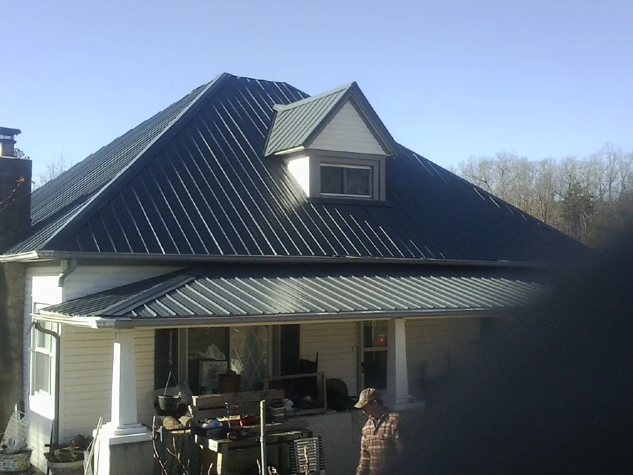 Dark blue standing seam metal roof with a dormer above a front porch in East Saint Louis
