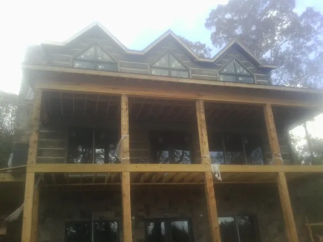 Dormers and porch framing on a large log home under construction — Roof Coating work by our crew in East Saint Louis