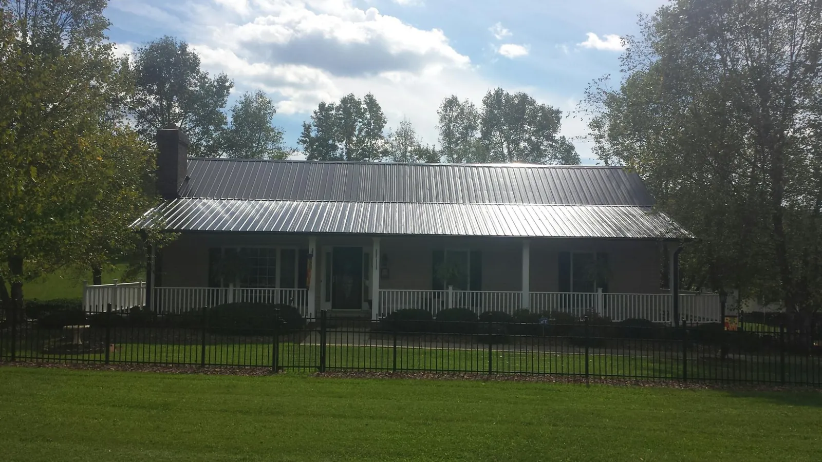 Gray metal roof on a brick ranch with a full width front porch — Gutter Guard Installation work by our crew in East Saint Louis