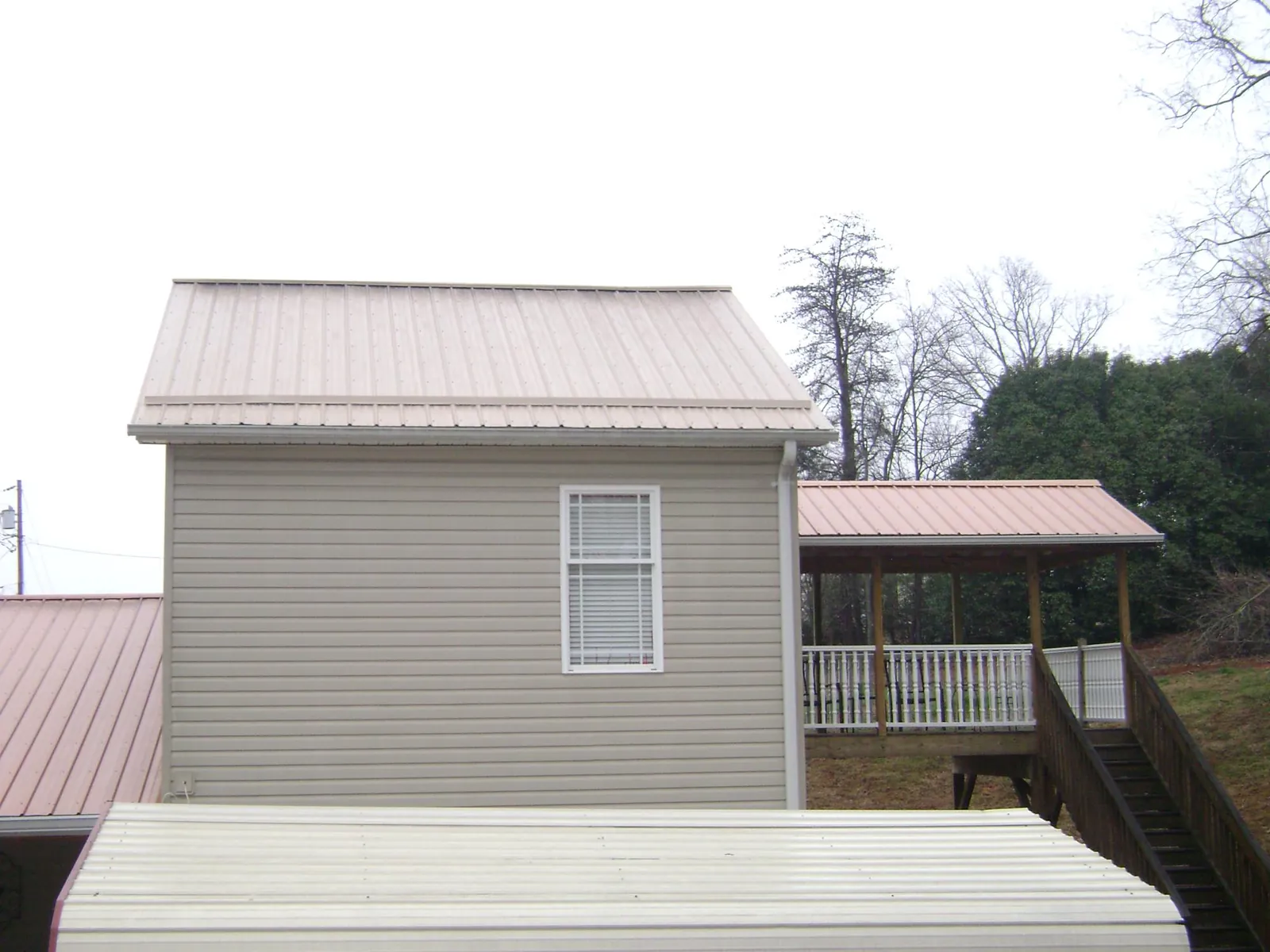 Tan metal roofs on a two story addition and attached porch, from a Roof Replacement job in East Saint Louis